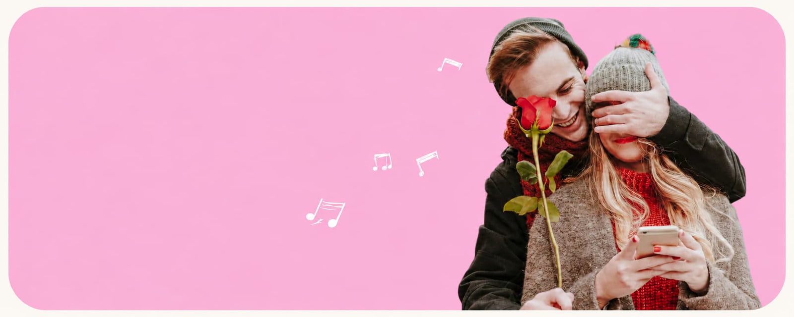 A couple in winter clothing, one covering the other's eyes with a gray beanie, with a red rose held to the nose, set against a solid pink background with floating white musical notes.