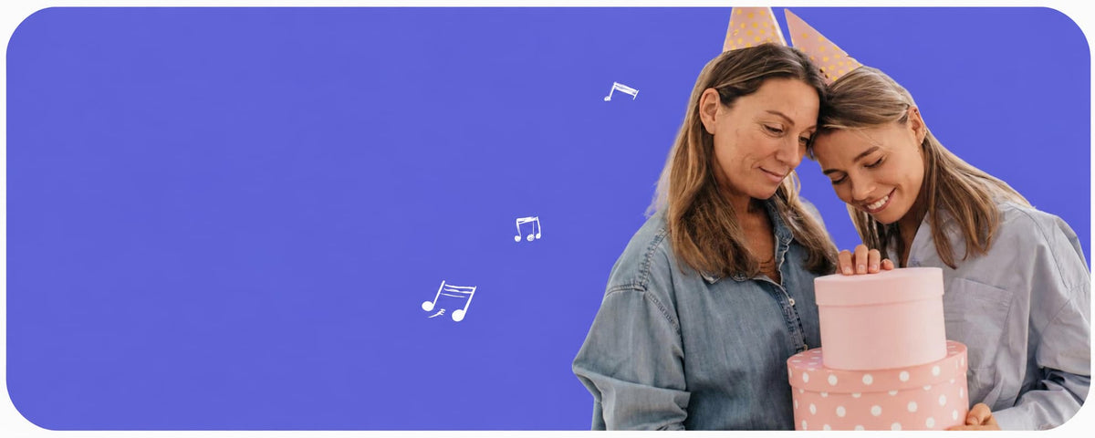 Two women wearing party hats and denim shirts celebrate with a two-tiered pink polka dot cake against a solid blue background with floating musical notes.
