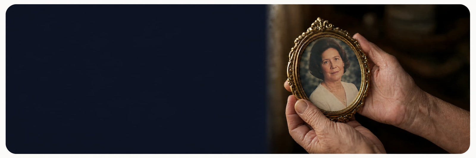 A pair of hands holding an ornate gold-framed portrait photo of a woman, shown against a dark navy blue background with a blurred warm-toned interior on the right.