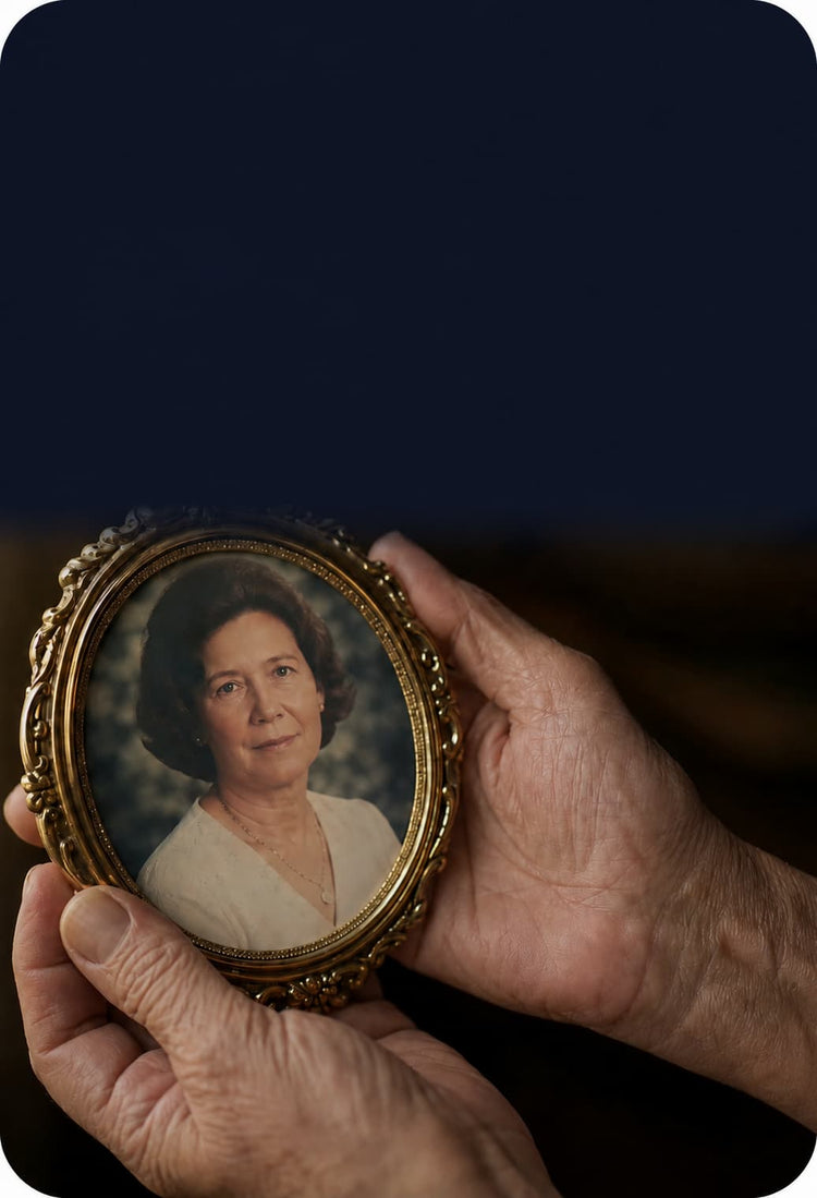 Elderly hands gently holding an ornate gold oval photo frame featuring a portrait of a woman, set against a dark navy background with soft lighting and open space above for text